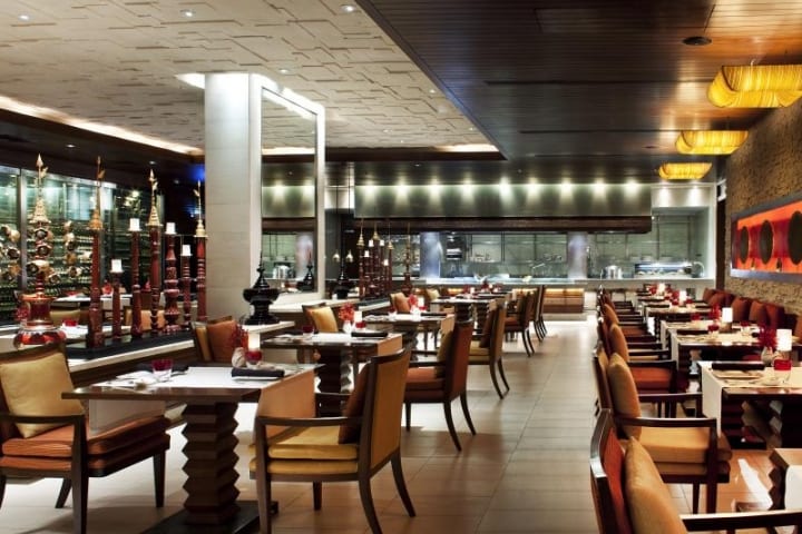 Dimly lit restaurant with tan chairs and a white mirror