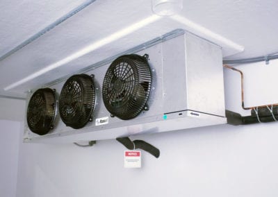 Inside of a Polar King industrial freezer with three black fans and white walls