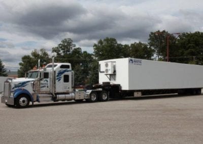 A white and blue semi truck pulling a white polar leasing cooler box rental